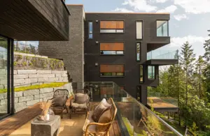 Bilde fra verandaen til en av leilighetene med utsikt over et annet leilighetsbygg og skog. 