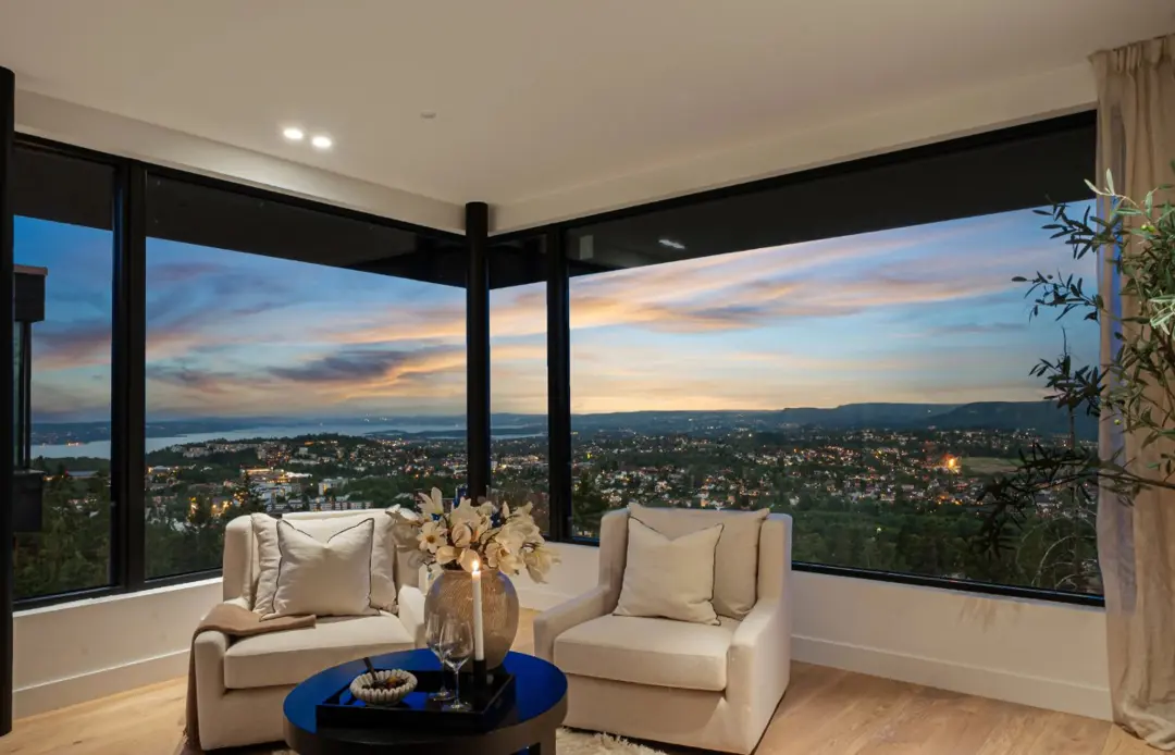Bilde av en leilighet med to lenestoler og nydelig utsikt over Oslo i bakgrunnen. 